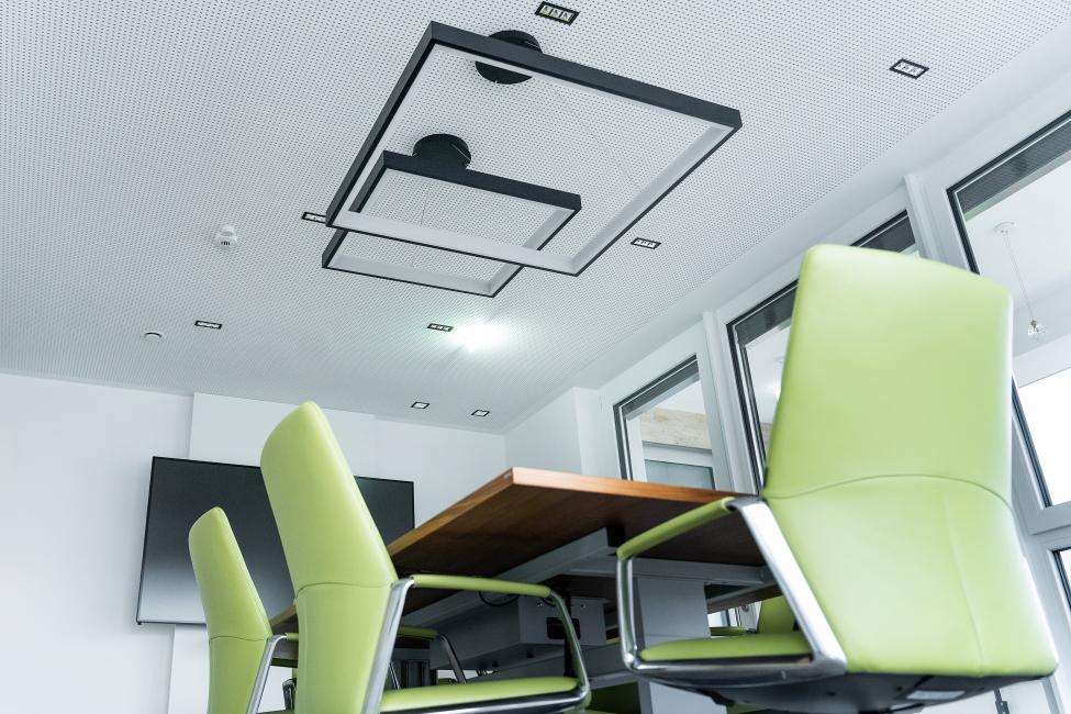 Viele Stühle an einem Tisch mit Deckenleuchten