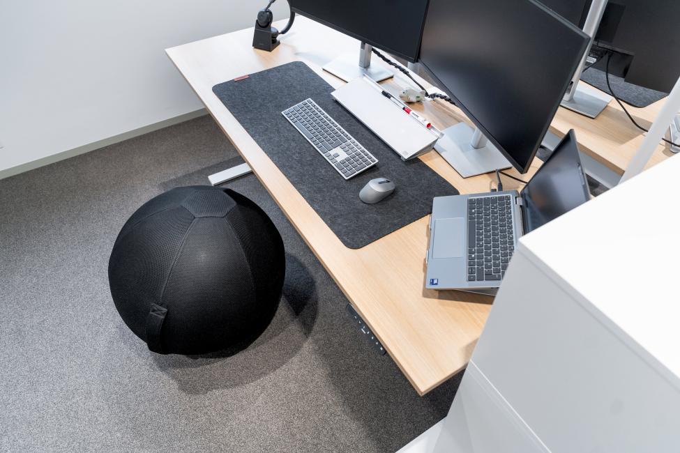 Ein Gymnastikball steht neben einem Schreibtisch